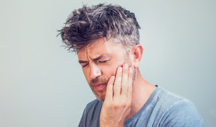 Man with dry socket cringes due to radiating pain in his jaw