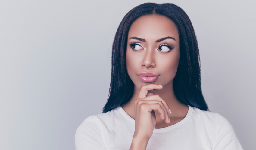 Dark-haired woman ponders what causes yellow teeth