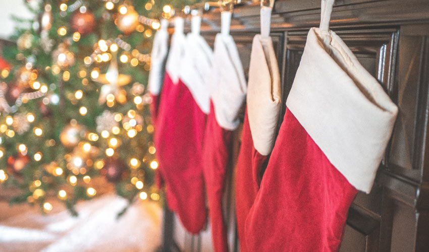 Closeup of red holiday stockings hanging on a brown mantle by a Christmas tree
